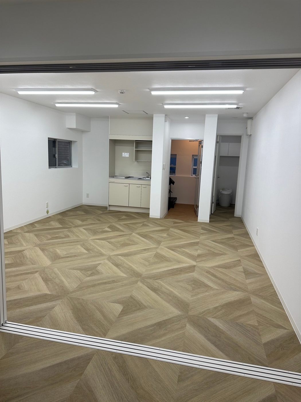 施工後：白い壁と寄木調の床の明るい事務所